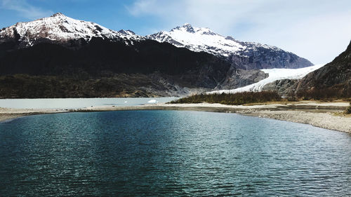 Scenic view of lake by snowcapped mountains against sky