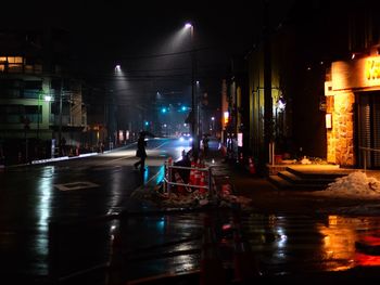 Reflection of illuminated buildings on wet street at night