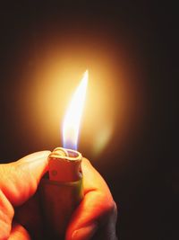 Close-up of hand holding lit cigarette lighter in darkroom