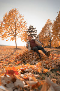 Low section of person sitting on tree during autumn