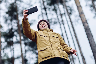Low angle view of young woman using mobile phone in winter