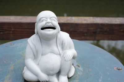 Close-up of buddha statue against water