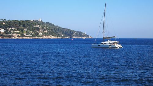 Sailboats sailing on sea against clear blue sky