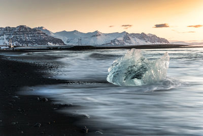 Scenic view of ice berg in sea against sky during sunset
