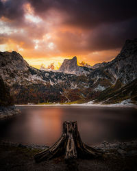 Scenic view of lake by mountains against sky during sunset