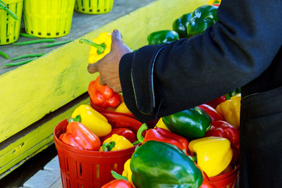 Midsection of person with red bell peppers