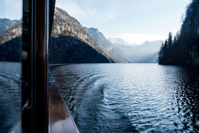 Cropped image of boat sailing on lake against mountains