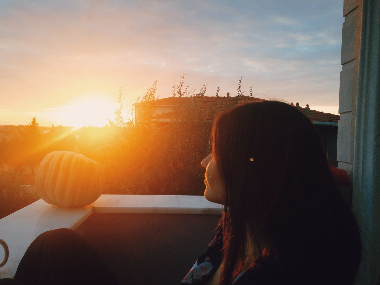 sun, sunset, lifestyles, sunlight, leisure activity, sky, sunbeam, technology, built structure, rear view, architecture, waist up, holding, headshot, three quarter length, sitting, window, building exterior