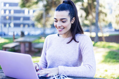 Smiling young woman using mobile phone outdoors