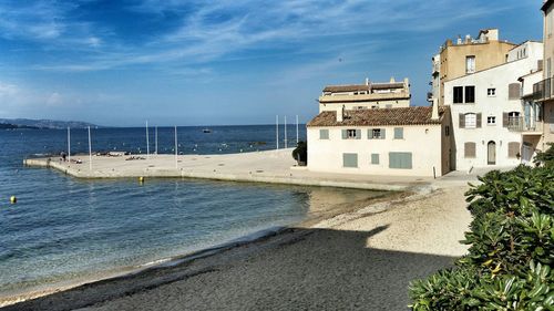 Houses by sea against blue sky