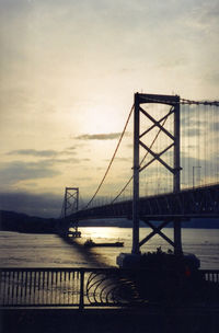 Bridge over river against cloudy sky