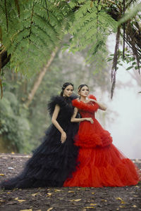 Portrait of smiling young woman in traditional clothing standing against trees