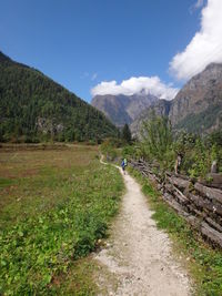 Road amidst trees and mountains against sky