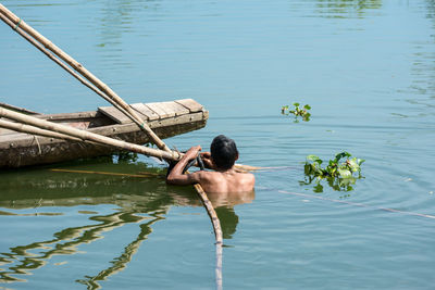 Rear view of shirtless man swimming in lake