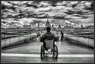 People at railroad station against cloudy sky