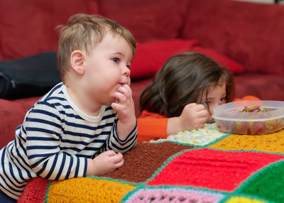 Brother and sister eating grapes while watching tv on halloween