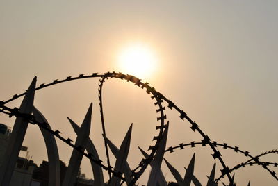 Low angle view of silhouette barbed wire against sky