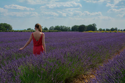 Woman standing on field against cloudy sky