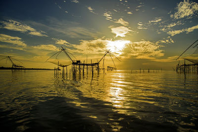 Silhouette pier over sea against sky during sunset