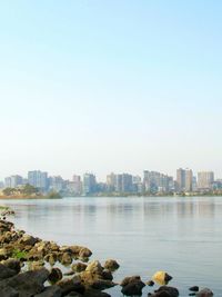 Sea by buildings against clear sky