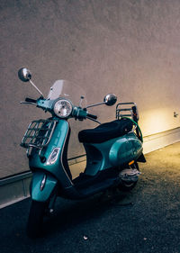 Vintage scooter parked by wall on street