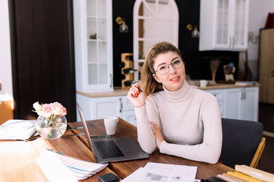 Young woman using phone while sitting on table