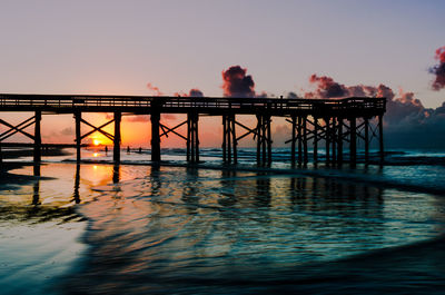 Silhouette of bridge over sea during sunset