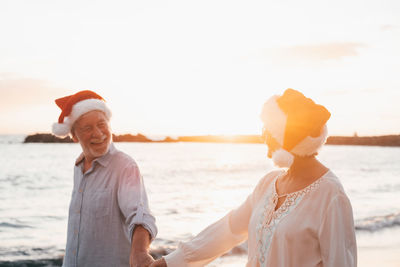 Rear view of smiling couple standing at beach