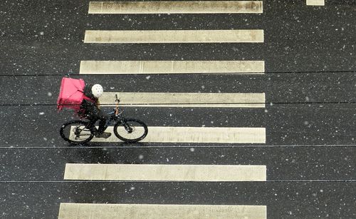 High angle view of man riding bicycle on road during rain