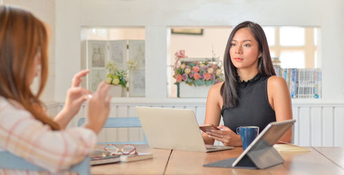 Portrait of woman using phone while sitting on table