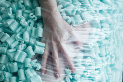Cropped hand of woman amidst sweet food seen through plastic