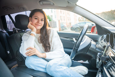 Young woman using phone while sitting in car