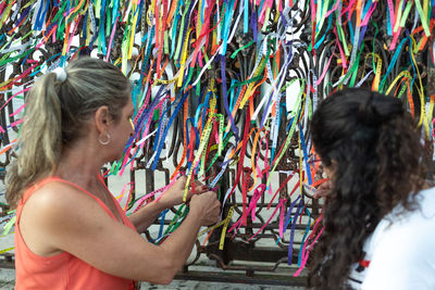 Portrait of two women placing colored ribbons on the church grid. 