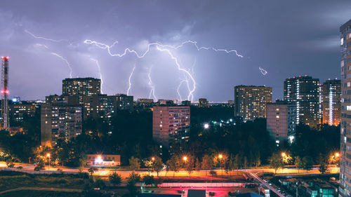 Lightning over illuminated buildings in city at night