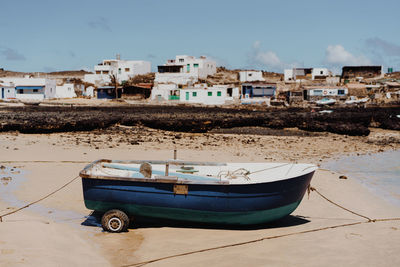 Boats moored on beach by buildings against sky