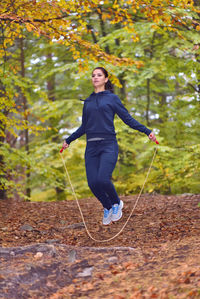 Young woman exercising with jump rope in forest