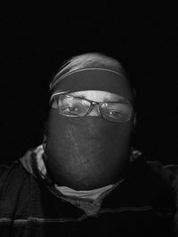 Close-up portrait of man wearing eyeglasses against black background