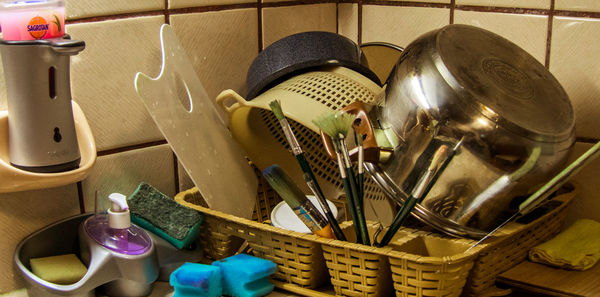 Paintbrushes and kitchen utensils in basket at home