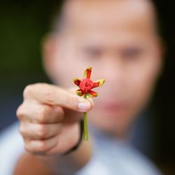 Close-up of woman holding flower against blurred background