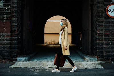 Woman in protective mask walks at city street