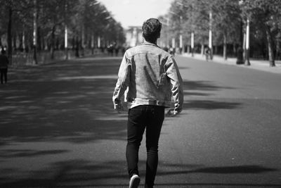 Grayscale portrait of young, stylish man dressed in denim clothes walking in the streets of london