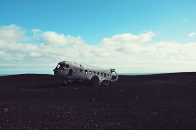 Abandoned airplane on desert against sky