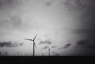 Low angle view of windmills on field against sky