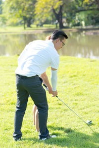 Full length of couple playing golf on field