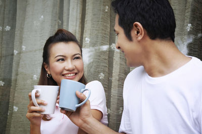 Close-up of a smiling young woman holding coffee