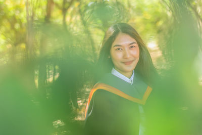 Portrait of smiling young woman standing in forest 