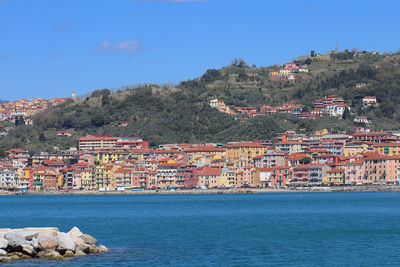 Aerial view of townscape by sea against sky