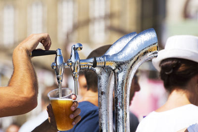 Close-up of man filling alcohol in glass from beer tap