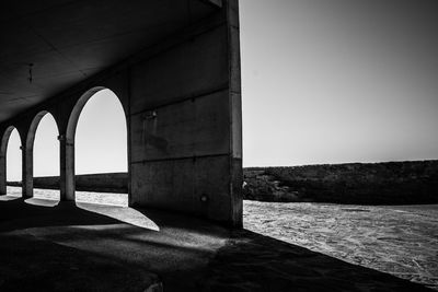 Arch bridge over sea against clear sky