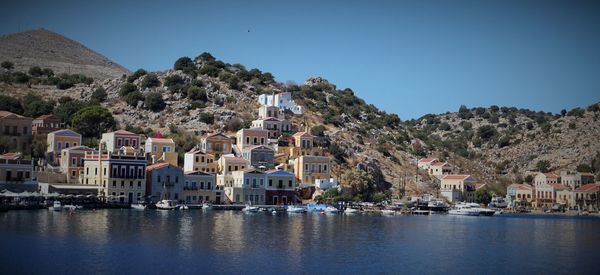 Sailboats in city by buildings against clear sky